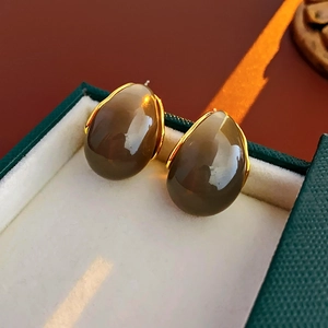 Detailed shot of coffee resin drop earrings with gold trim in a dark green velvet box
