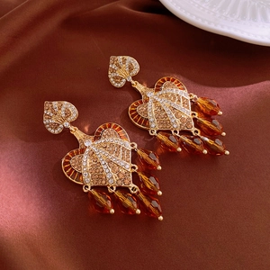 Macro detail of vintage gold heart earrings with amber crystal beads and baroque fringes