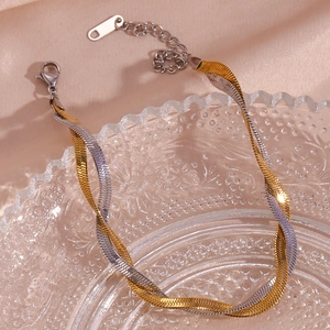 Detail of two-tone gold and silver twisted blade chain anklet on pink silk