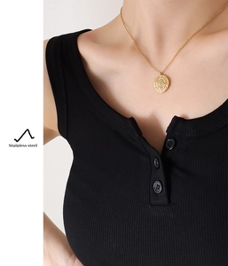 Close-up of golden stainless steel sun medallion necklace with crystals on model