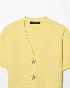 Détail de la robe en tricot jaune avec boutons en strass étoile de mer et décolleté en V