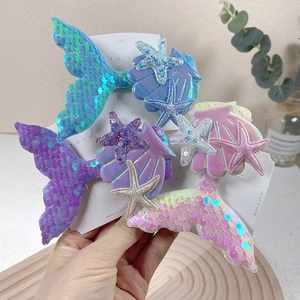 Close-up of sequined mermaid tail, seashell, and starfish hair clips in pastel colors