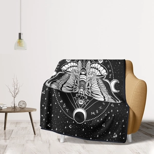 Close-up of flannel blanket showing moth and zodiac patterns on a soft sofa