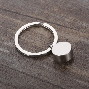 Détail d'un pendentif cylindrique en acier inoxydable argenté avec anneau sur bois