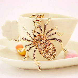 Creative gold spider keychain with sparkling diamonds and metal lobster clasp on a cup