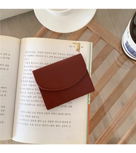 Detail view of red leather card holder with fine stitching on a vintage book