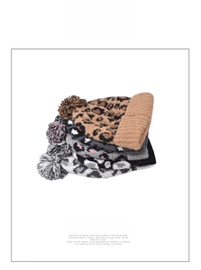 Close-up of leopard print knit beanies with fluffy pom poms in various neutral colors