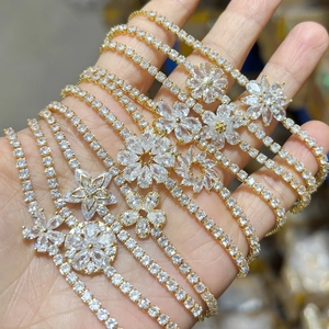 Détail de bracelets réglables plaqués or avec des motifs floraux en zircons étincelants