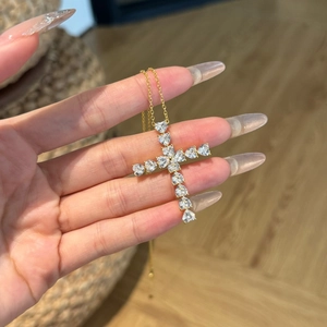 Detail of a gold cross pendant crafted with eleven sparkling heart-shaped zircon stones