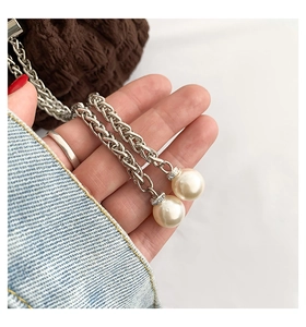 Close-up of elegant silver chain straps featuring round white imitation pearl pendants