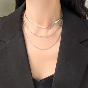 Close-up of triple layered silver chains featuring snake, figaro and round link styles