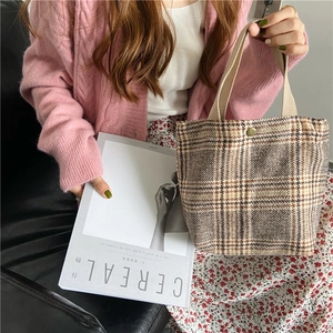 Detailed view of the plaid wool fabric texture and sturdy canvas handles on a tote bag