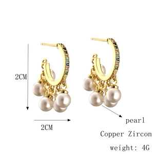 Detail of C-shaped gold-plated hoop earrings with multicolor zircon and white pearls