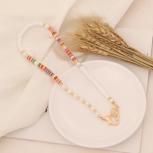 Bohemian clay bead necklace with pearls and gold heart clasp on white display