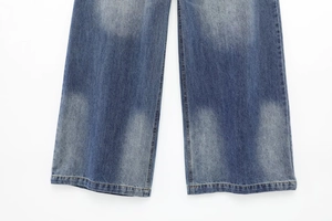 Detail of washed denim pants hem showing double-stitched seams and blue fabric texture