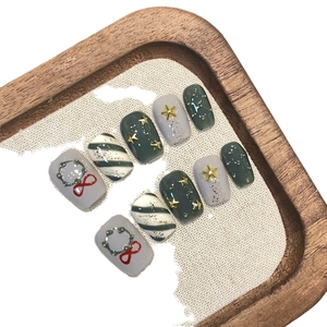 Short dark green press-on nails with Christmas wreath, gold stars and festive patterns