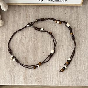 Detail view of woven brown leather cord with colorful ceramic beads and metal clasp