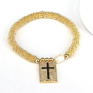 Detailed close-up of a golden beaded bracelet with a zircon cross charm and natural pearl