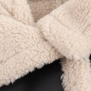 Close-up of soft cream faux shearling texture on a winter jacket showing plush material