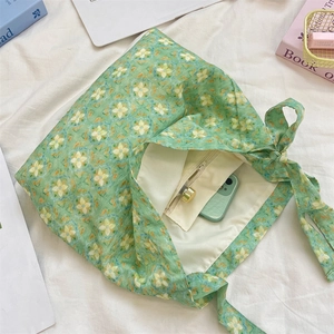Detail of the green floral tote bag interior showing the zipper pocket and phone storage