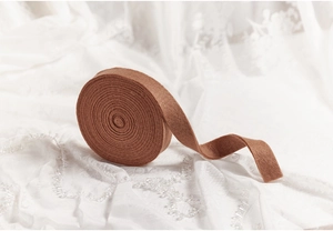 Macro shot of brown wool felt ribbon roll for DIY Christmas decorations on lace
