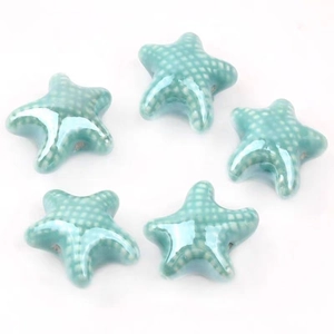 Detailed view of five cyan blue ceramic starfish beads with white polka dot glaze finish