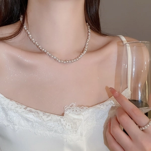 Detail of elegant pearl necklace with rhinestone beads on model's collarbone