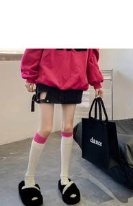 Detail of white knit knee-high socks paired with black fuzzy slippers and a mini denim skirt