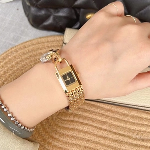 Close-up of a luxury gold chain watch with black square dial worn on a model's wrist
