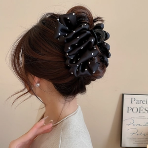 Detailed side view of a large black satin polka dot bow hair claw clip for elegant styling