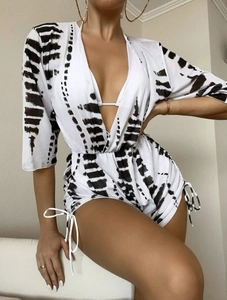 Detail of white animal print romper with deep V-neck and drawstring side ties for resort wear