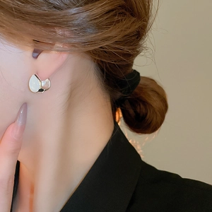 Minimalist silver C-shaped hoop earrings with white teardrop stone on model