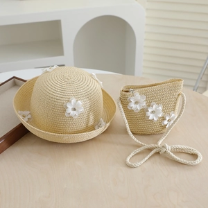 Close-up of woven straw hat and matching bag with white fabric flowers for toddlers
