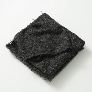 Close-up of dark grey plaid poncho scarf showing soft knit texture and tassel edges