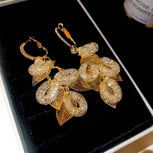 Elegant gold leaf tassel drop earrings with sparkling cubic zirconia on black velvet