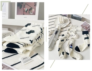 Detail of white cotton socks with cute black cat patterns and stripes in home setting