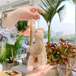 Close-up of fluffy brown alpaca plush keychain with silver metal clip being held
