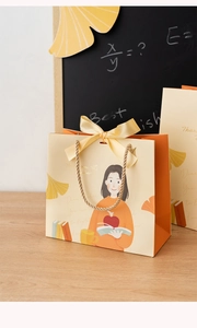 Detail of teacher gift bag featuring warm illustrations and silk bow on wooden desk