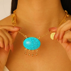 Detail einer Boho-Goldkette mit Türkis-Anhänger, kleinen Glöckchen und antiken Münzen
