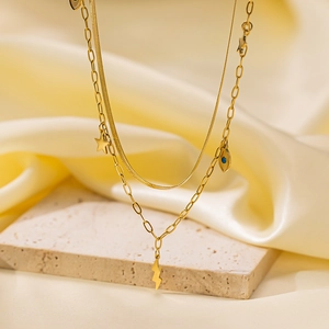 Macro detail of 18K gold-plated layered necklaces with star and evil eye charms