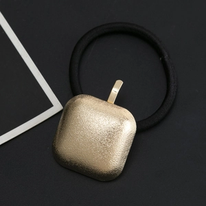 Minimalist black elastic hair tie featuring a matte gold square geometric metal charm