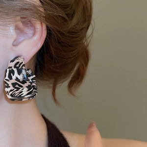 Close-up of vintage large C-shaped hoop earring with leopard print leather pattern