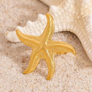 Golden starfish ring with textured details on natural sand beach background