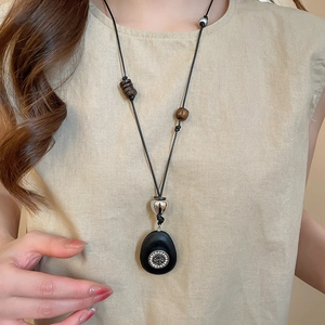 Detailed view of an oval cross heart pendant necklace on a linen top for women