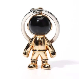 Close-up of a golden astronaut keychain with a polished finish and black visor