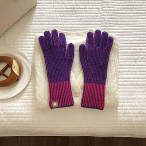 Detalle de guantes de punto morados y rosas con puños acanalados y etiqueta decorativa