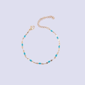 Detailed macro view of a gold-plated lip chain bracelet with turquoise enamel beads
