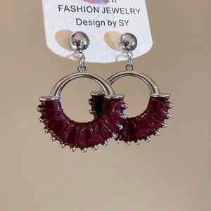 Detail of silver round hoop earrings featuring dark burgundy woven leather and metal beads