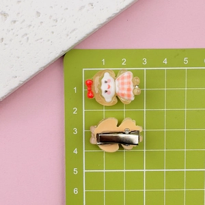 Detail of cartoon girl resin hair clip with silver metal snap back on measuring mat