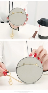 Detail of round grey cat-ear coin purse with gold zipper and metal keychain clip